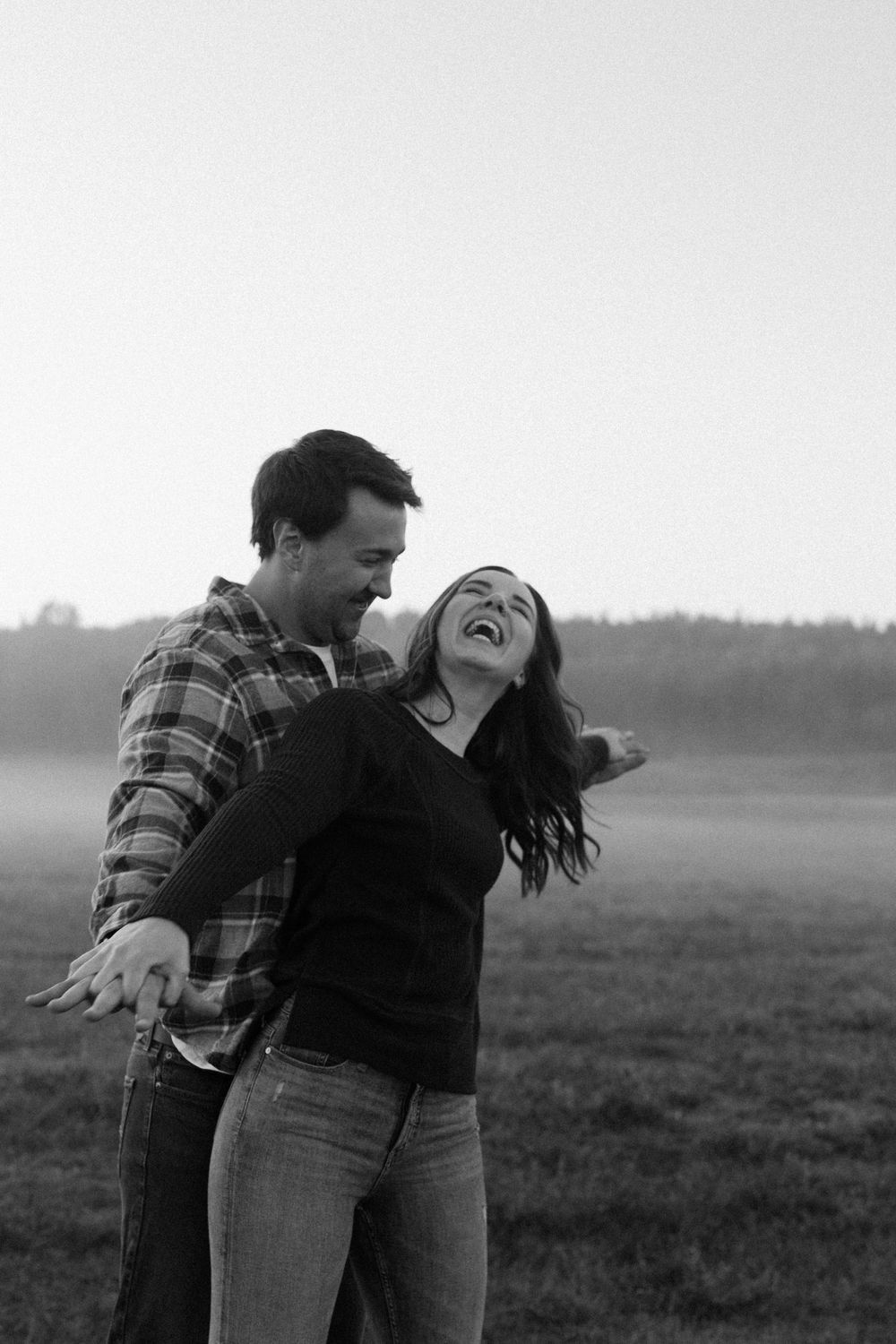 A candid black and white photo of a couple laughing during a playful dip.