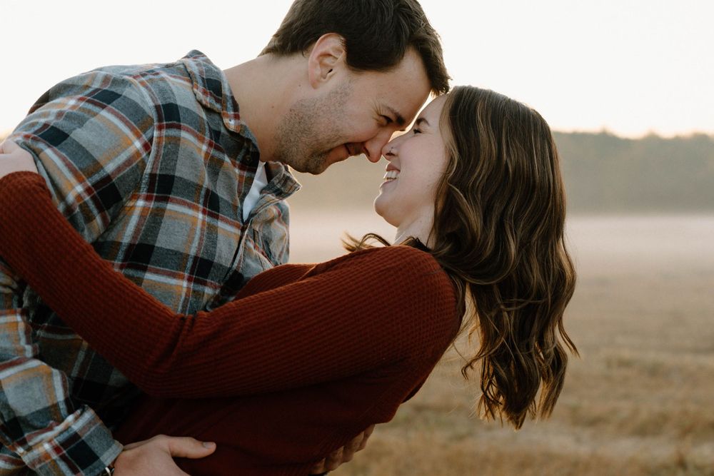 A couple wrapped in an intimate embrace against a misty outdoor backdrop.