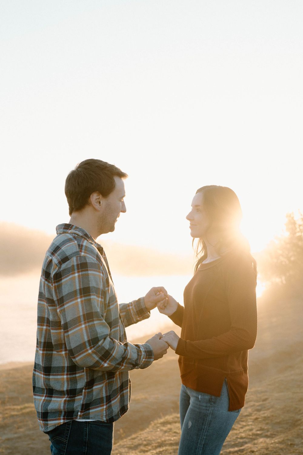 Silhouettes of a couple in golden sunlight during what appears to be a proposal.