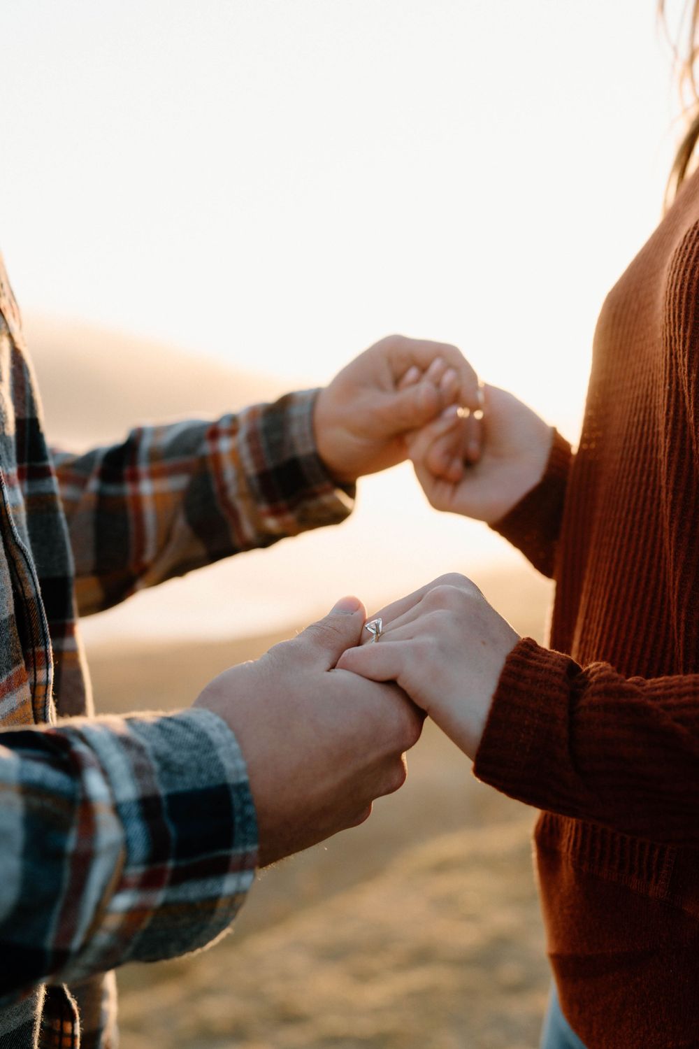 Close up of hands exchanging something between two people in warm sunlight.