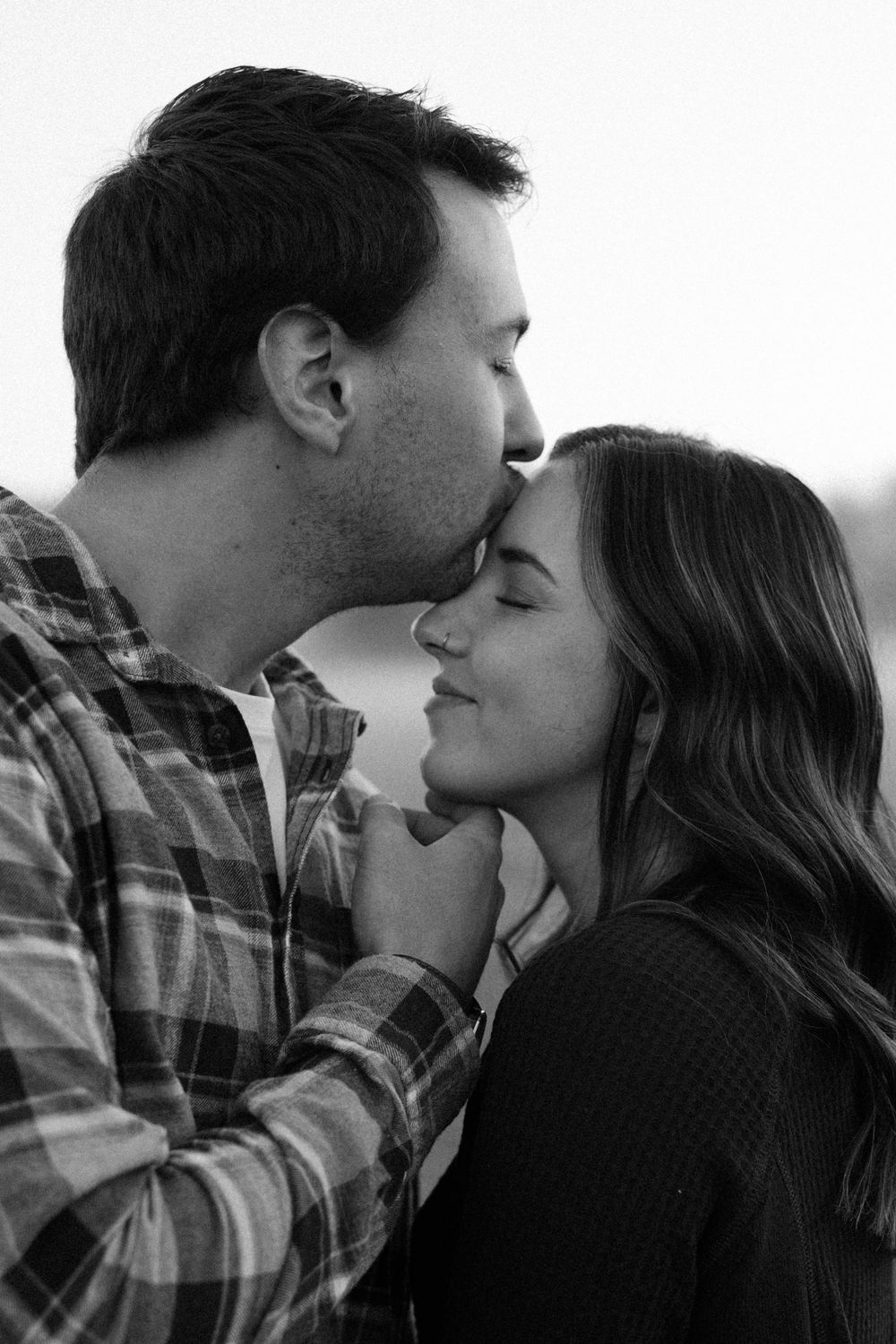 Close-up black and white portraits of a couple sharing tender moments outdoors.