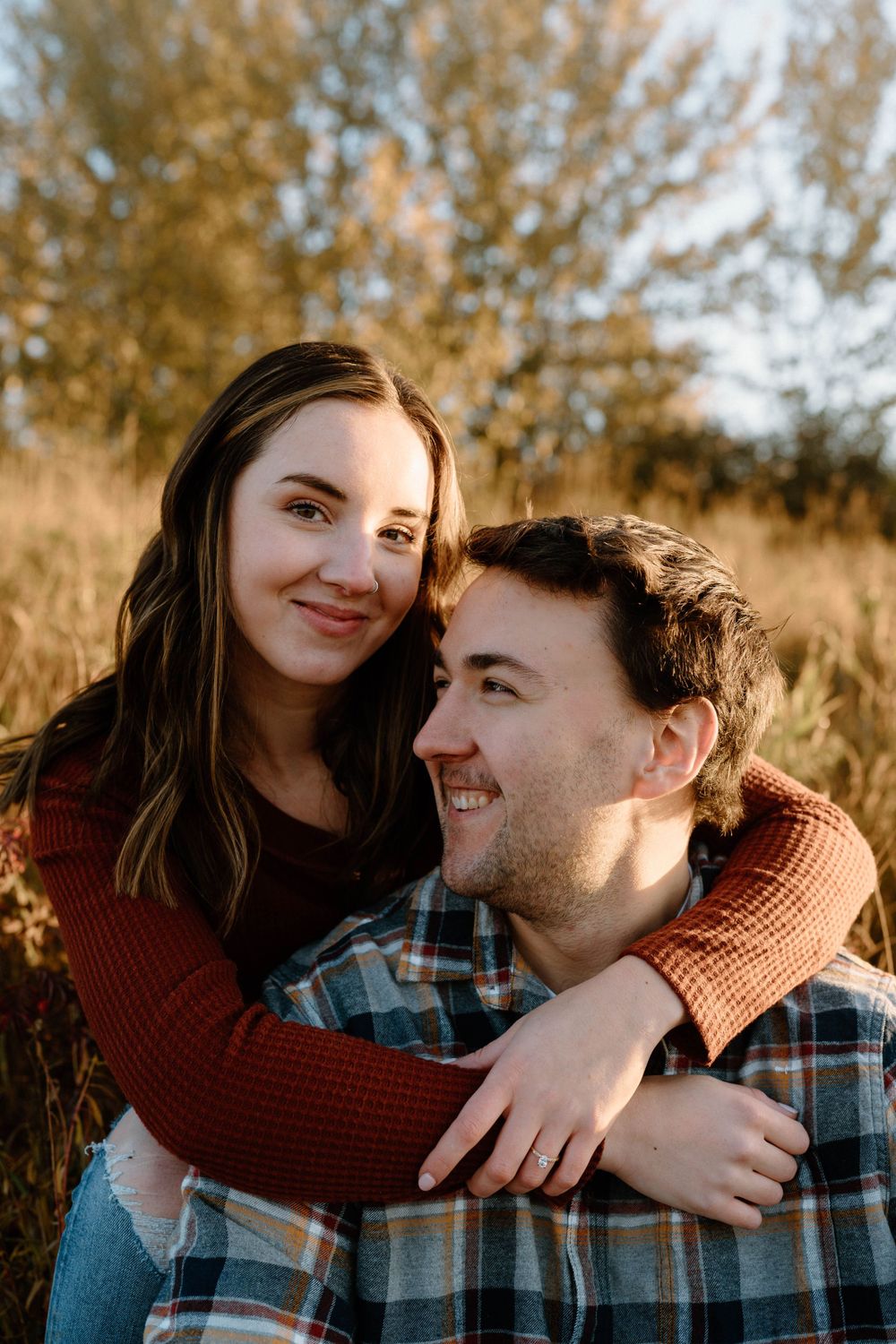 A joyful autumn portrait of a couple embracing outdoors during golden hour.