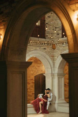 Intimate moment captured through stone archway in historic building interior.