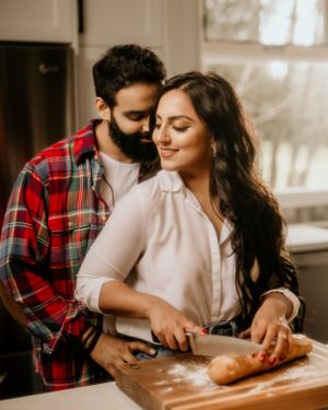 Couple sharing intimate moment while baking together in sunlit kitchen.