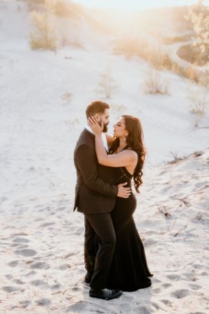Romantic embrace on sandy beach during golden sunset hour.