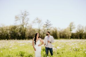 A romantic outdoor photoshoot in a sunny wildflower meadow with trees in the background.