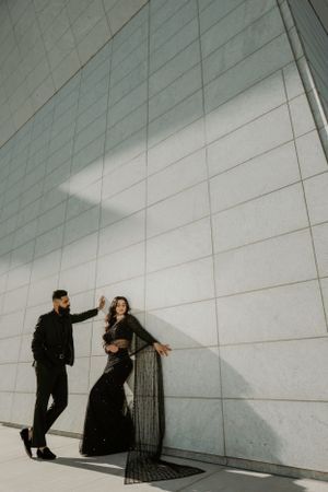 Modern architectural fashion shot against geometric white wall with dramatic shadows.