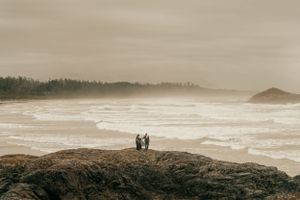 Atmospheric seascape photo with silhouettes standing on coastal rocks.