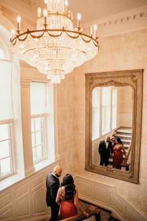 Elegant interior with crystal chandelier and large mirror reflecting a romantic moment on staircase.