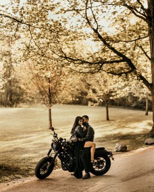 A romantic motorcycle engagement session under blooming trees in autumn.