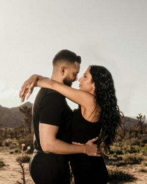 Romantic desert photoshoot with mountains and joshua trees in warm golden light.