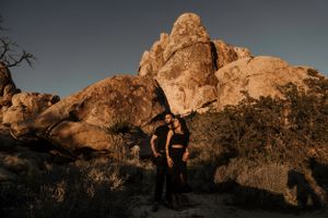 Couple embracing against dramatic desert rock formations during golden hour.