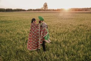 A couple in traditional dress share an intimate moment in a wheat field at sunset.