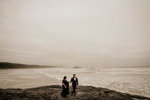 Moody black and white photograph of couple on rocky Pacific Northwest coastline.