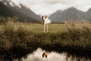 A couple creates a reflection in a mountain pond during their wedding photoshoot.