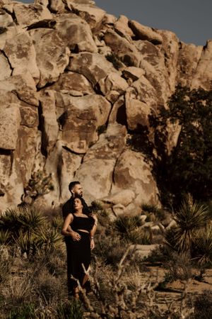 A romantic portrait against towering desert rock formations in warm sepia tones.