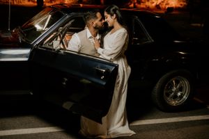 An intimate moment shared between a couple by their vintage car at night.