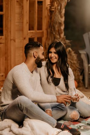 A cozy indoor couple portrait session showing two people sharing an intimate moment on blankets.