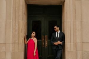 A couple shares a playful moment by an elegant doorway during a formal photoshoot.