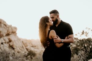 An intimate portrait of a couple sharing a tender moment in front of desert rock formations.