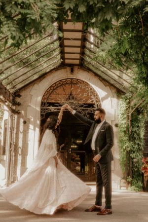 A flowing white dress twirls under a vine-covered walkway.