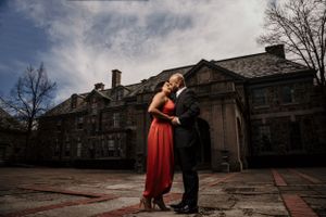 Couple in formal attire share romantic moment outside historic stone building.