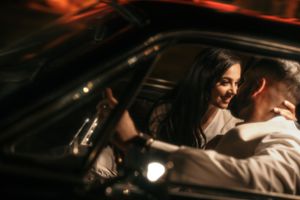 A romantic moment captured inside a vintage car during a nighttime photo session.