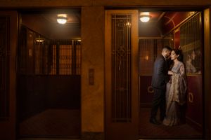 Couple sharing intimate moment in dimly lit vintage hallway with ornate details.