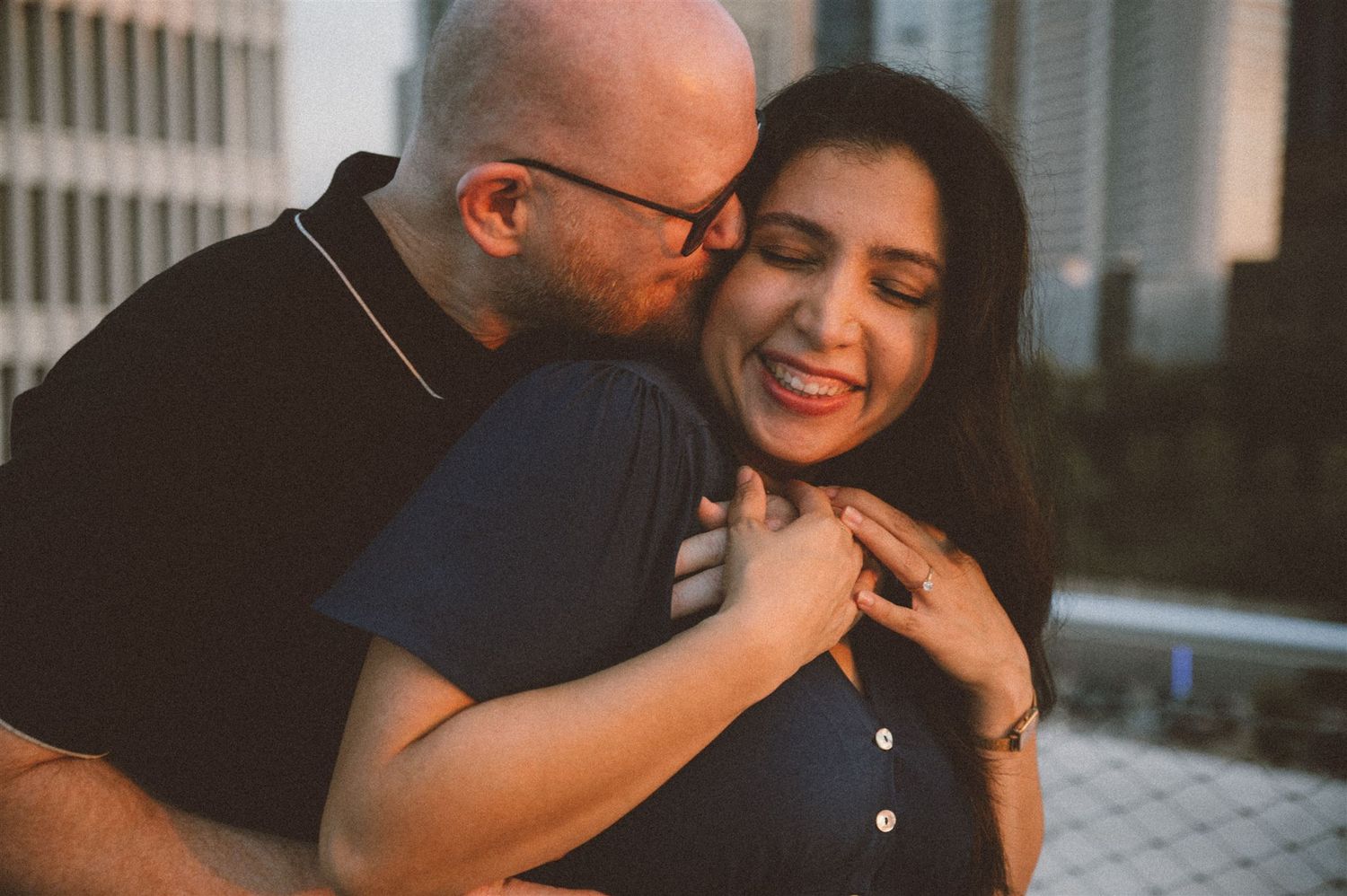 Intimate moment shared between a couple during a golden hour photoshoot on a rooftop.