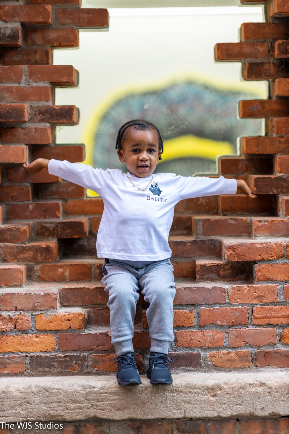 little boy with arms out to side in grey long sleeve shirt and jogging pants