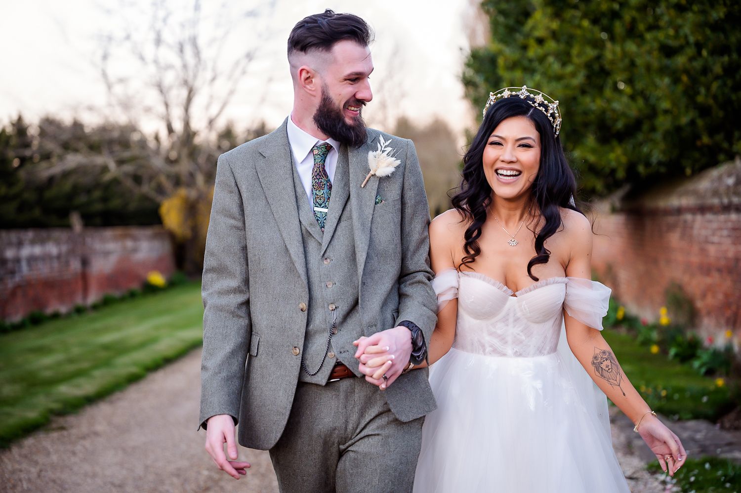 Happy newlyweds walking and laughing together in garden setting.