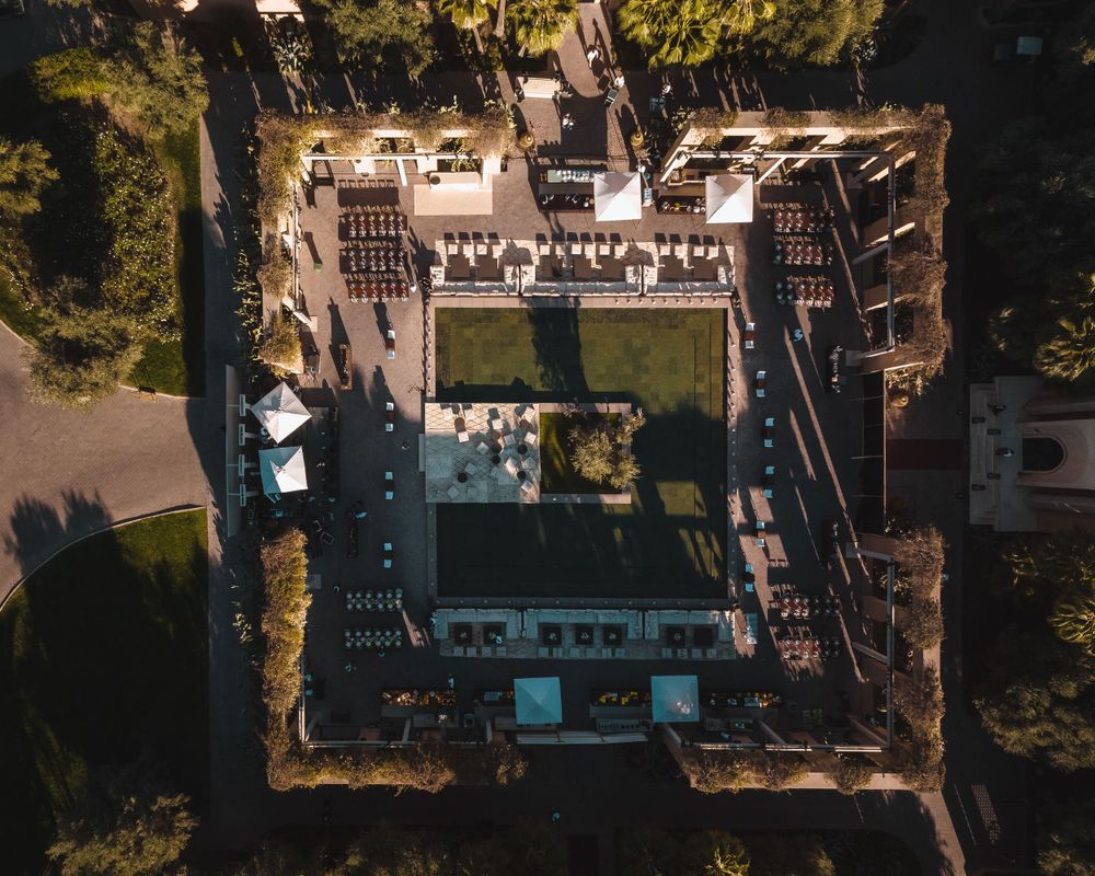 Symmetrical aerial view of a courtyard building with swimming pool and gardens.