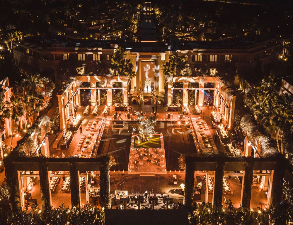 Aerial night view of an illuminated outdoor event venue with symmetrical architecture and garden layout.
