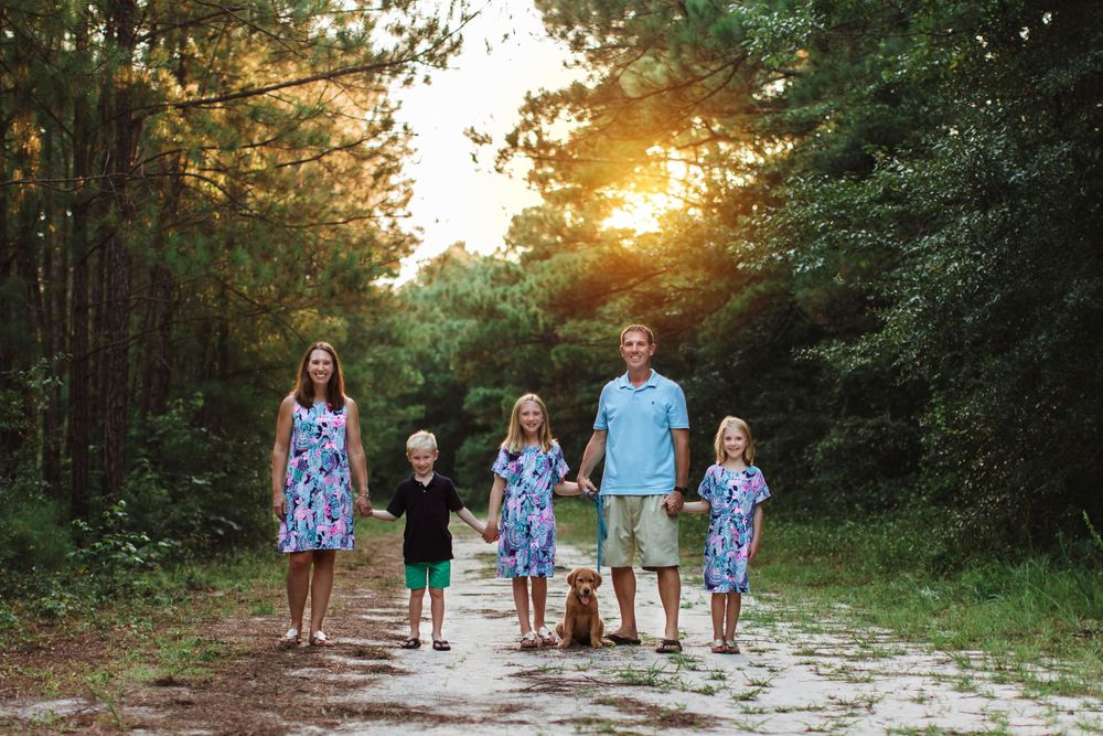 A group walks together on a dirt path through the woods at sunset.
