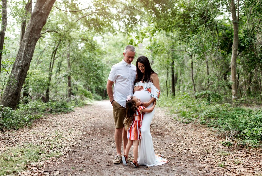 A family shares an intimate moment on a forest trail during a summer photo session.