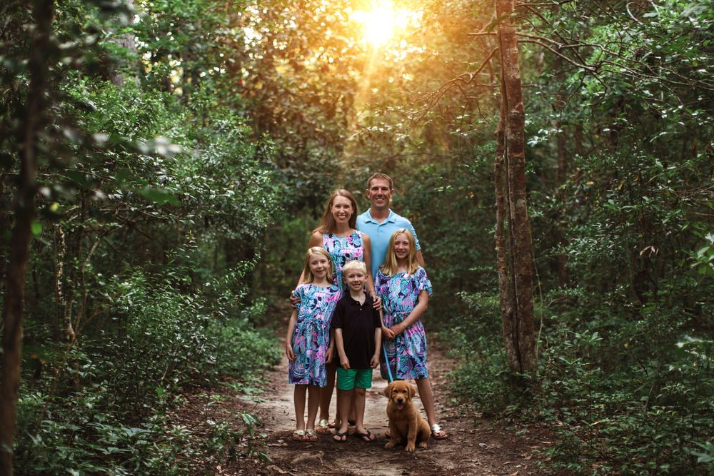 A group poses for a photo on a wooded trail during golden hour.