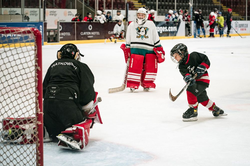 boy taking shot on ice hockey goalie sports photography