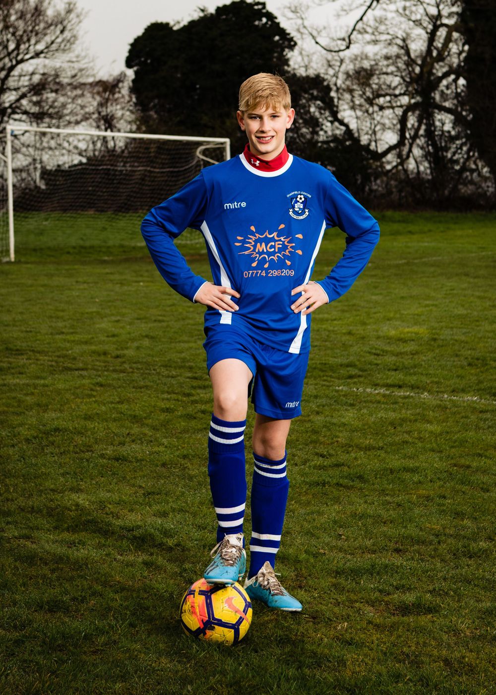 Youth football portrait of a young player standing on the pitch with a football