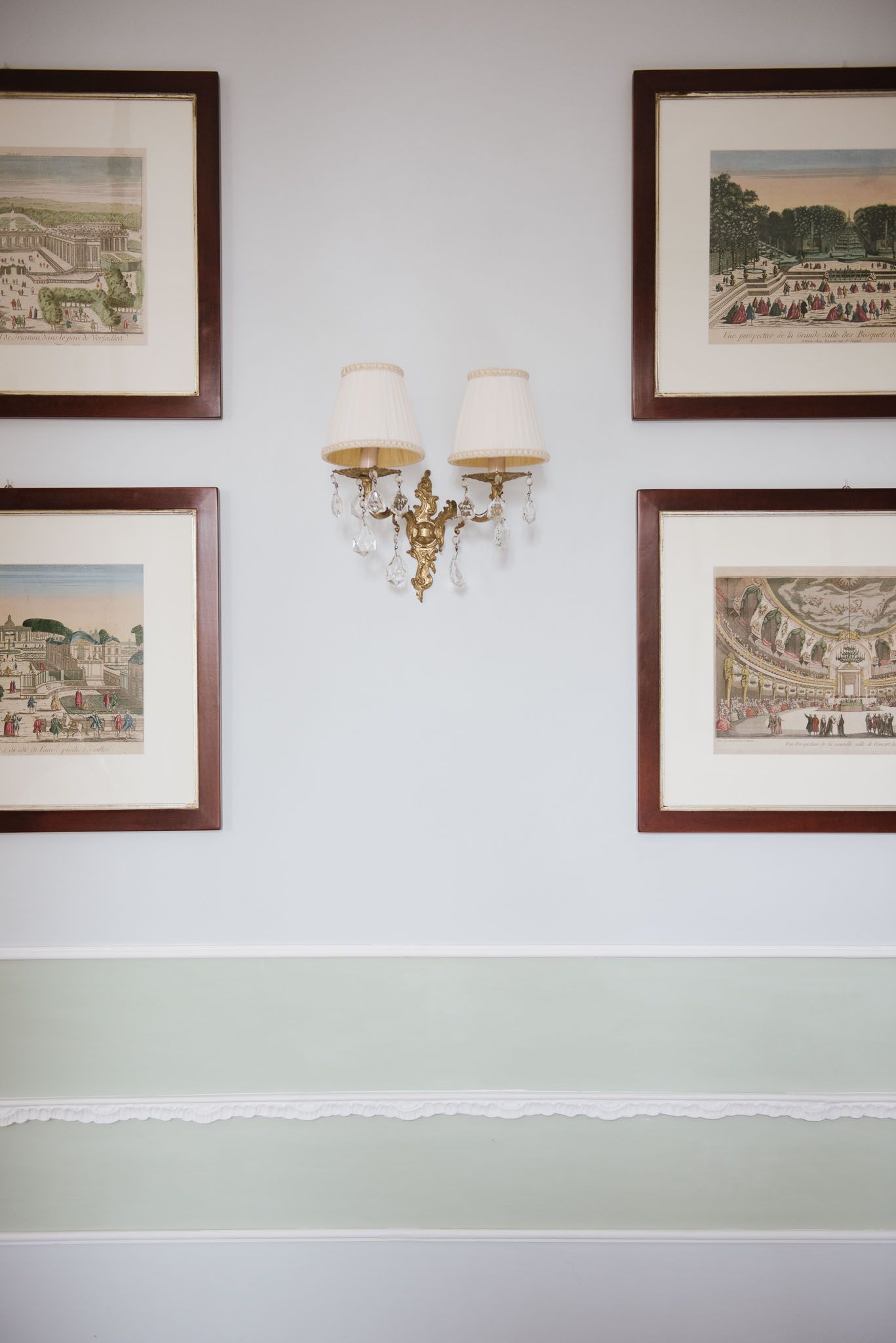 Elegant wall decor featuring framed vintage prints and crystal wall sconce in traditional style.