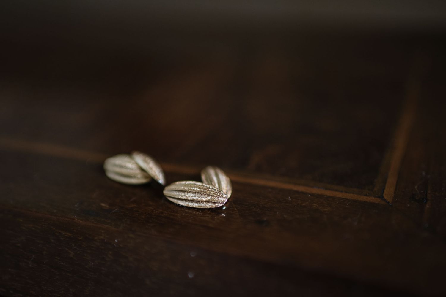 Delicate diamond earrings on dark wooden surface in macro detail.