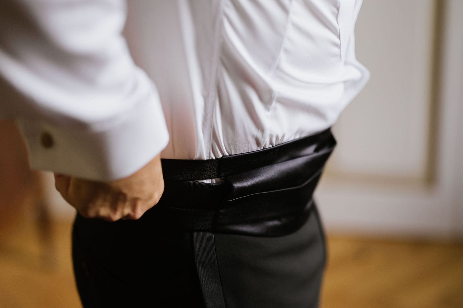 Close-up detail shot of hands adjusting a formal black suit.
