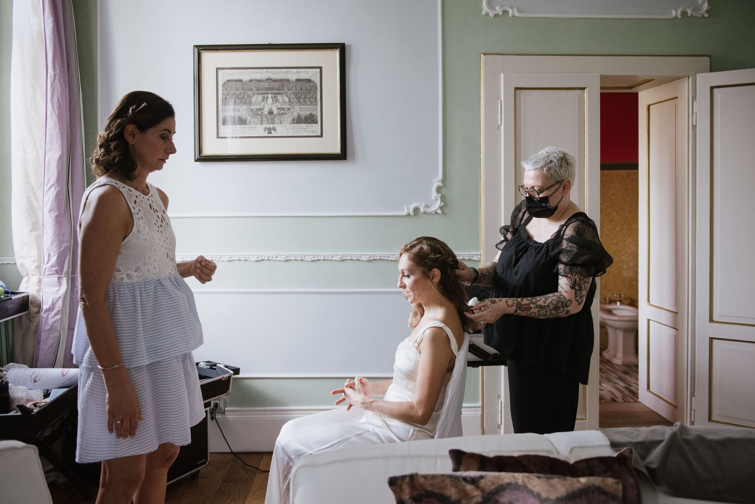 Wedding preparation scene with three people in elegant room with mint green walls.