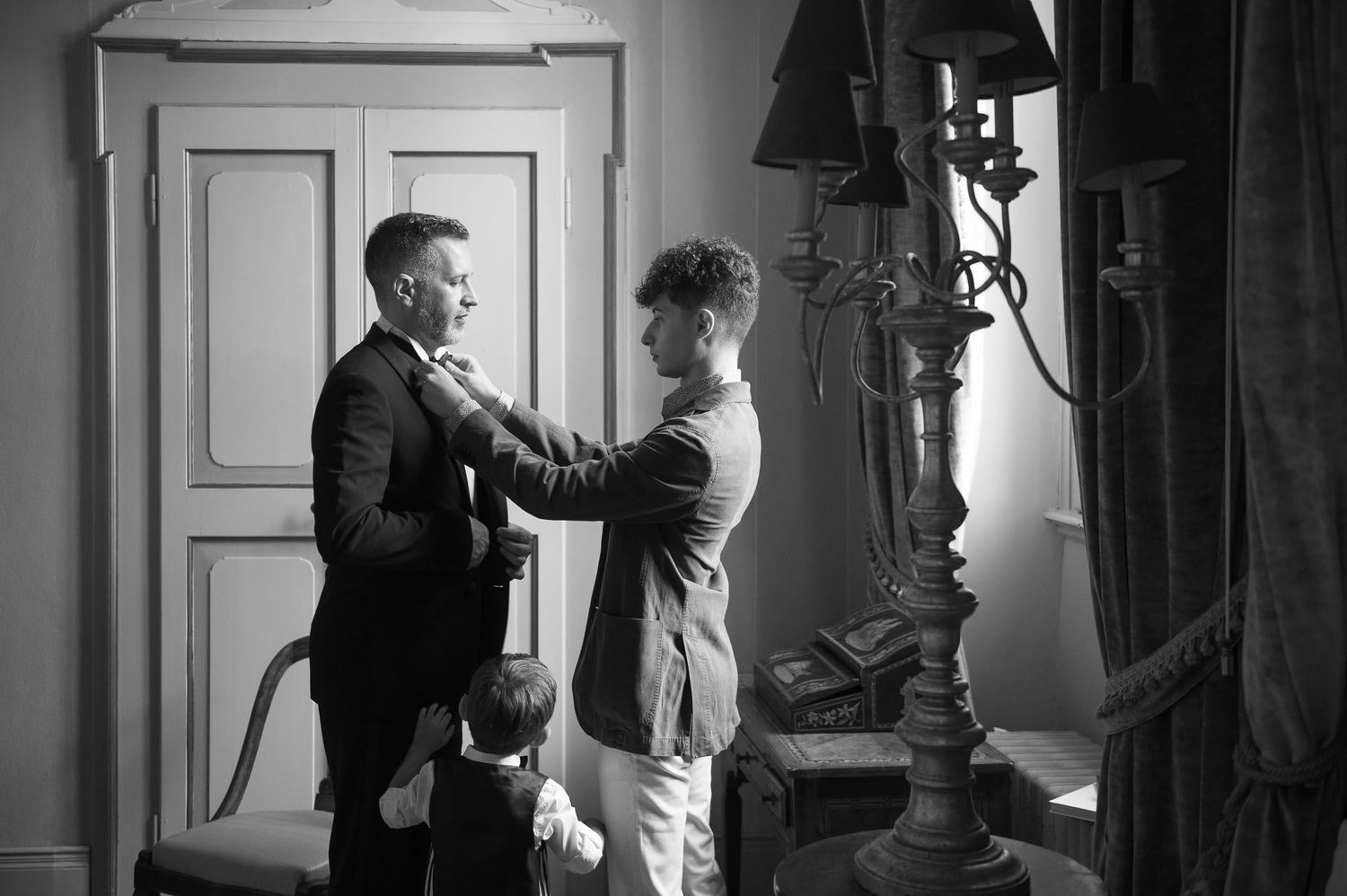 Black and white image of formal preparation with child watching nearby.