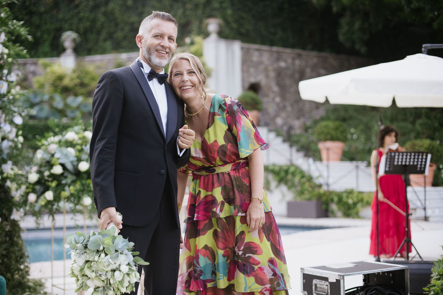 Couple smiling together at garden wedding with white umbrellas in background.
