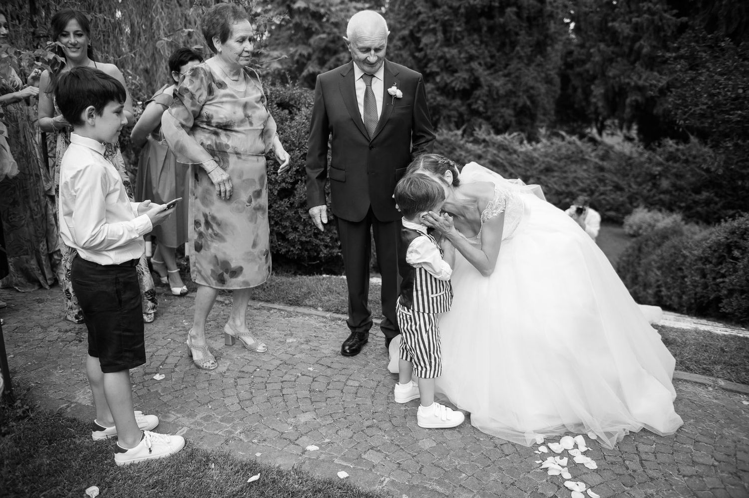 Black and white candid moment with young guest at outdoor wedding celebration.
