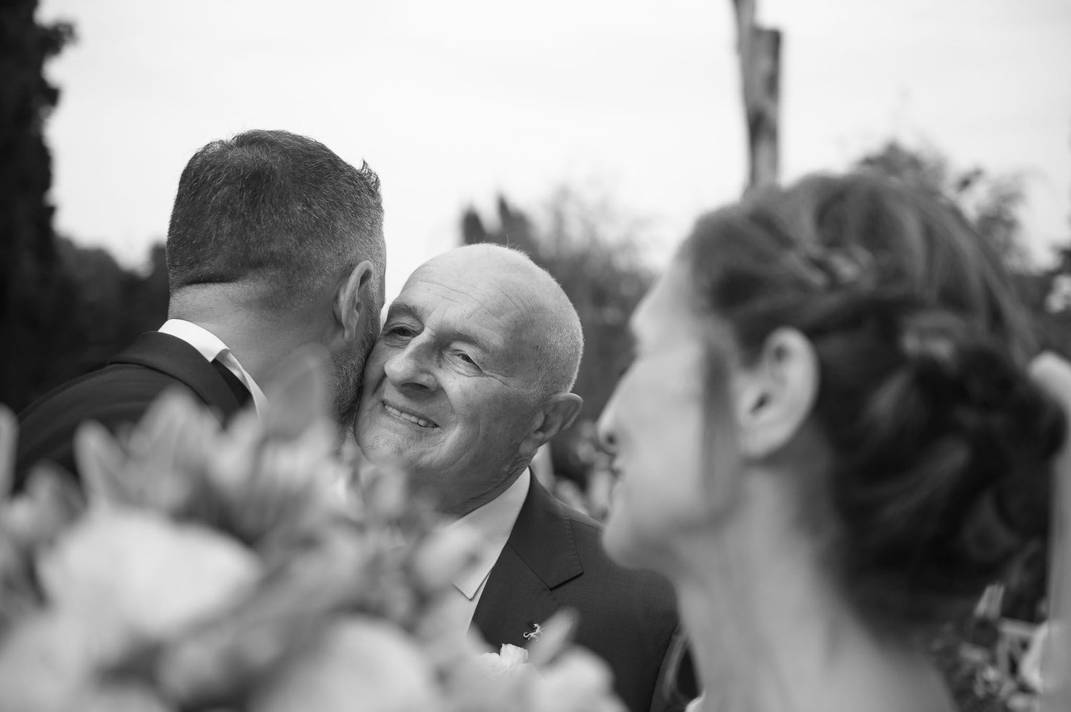 Candid black and white moment captured during outdoor wedding celebration.