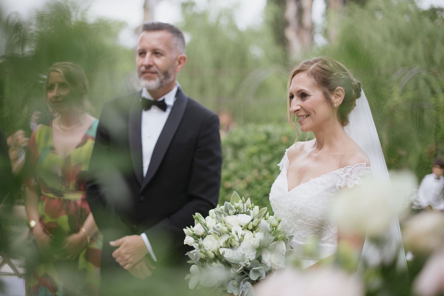Romantic garden wedding scene with white floral bouquet and soft focus greenery.