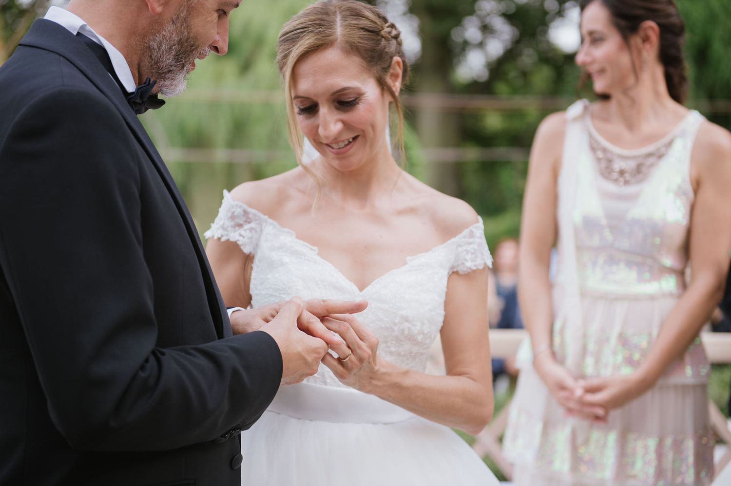 An intimate ring ceremony moment during an outdoor garden wedding with elegant attire.