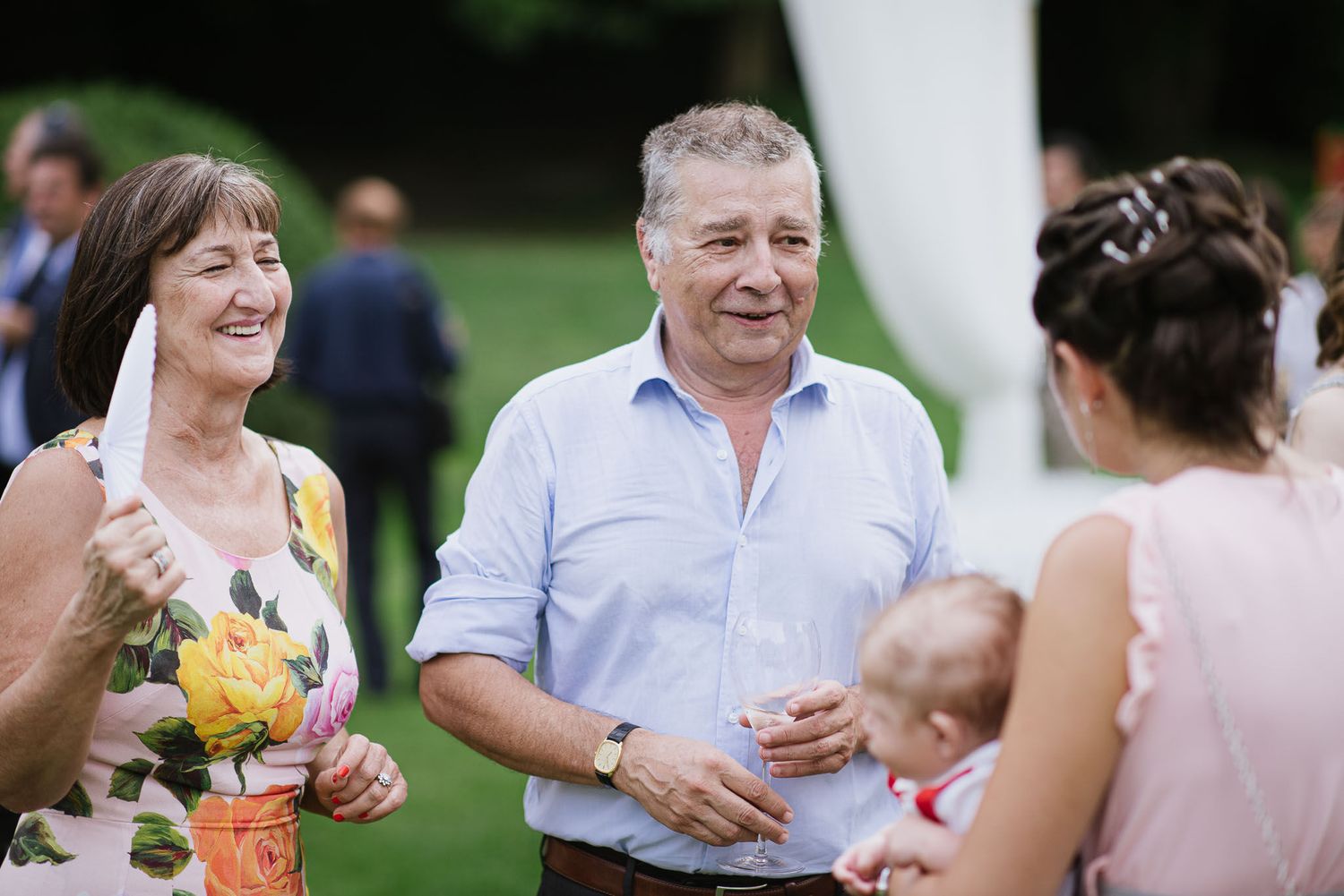 Wedding guests enjoying conversation and refreshments at an outdoor garden reception.