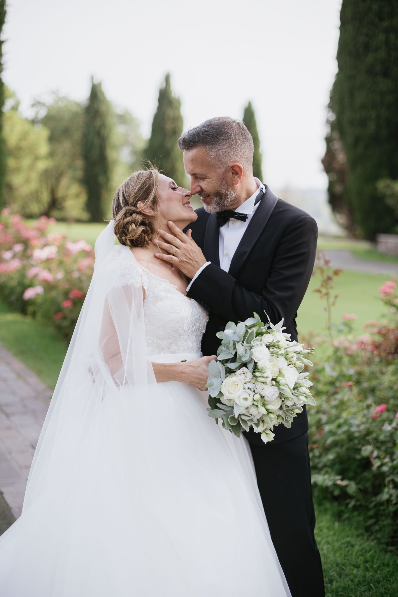 Intimate wedding moment captured in a garden setting with white floral bouquet.
